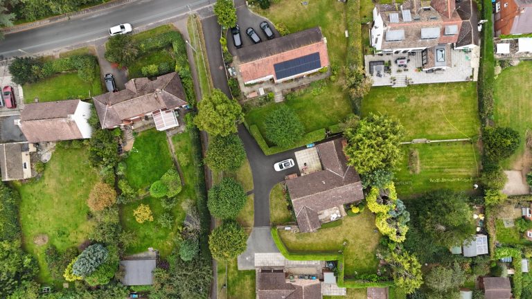 Aerial view of suburban houses with gardens and a winding road.